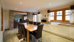 A spacious kitchen with a dining area, stone wall, wooden cabinets, and a large window.