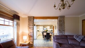A living room with a fireplace, a dining area, and a kitchen.