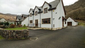 A two-story house with a stone foundation, a garage, and a driveway.