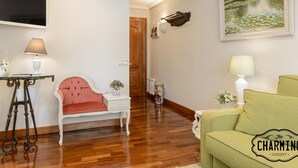 Ein Wohnzimmer mit einem roten Polsterstuhl, einem grünen Sofa, einem weißen Beistelltisch und einem Bild an der Wand.
