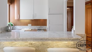 Eine moderne Küche mit weißen Schränken, einer Arbeitsplatte aus Granit und einer Küchenrückwand aus Stein.