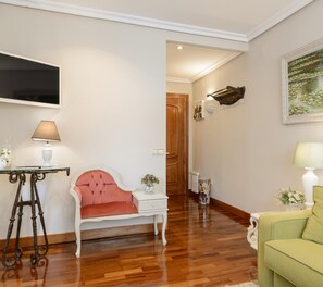 A living room with a red upholstered chair, a green sofa, a white side table, and a painting on the wall. - Argüelles, cozy apartment for 4 in the center, AC (Madrid)