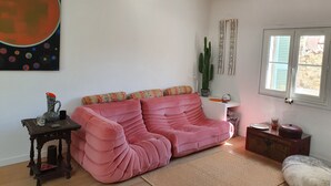 Un saló agradable amb un sofà rosa, un cactus i obres d'art a les parets.