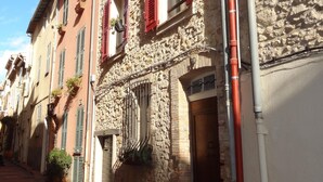Un carrer estret amb edificis de pedra, persianes vermelles i una bicicleta aparcada a l'exterior.