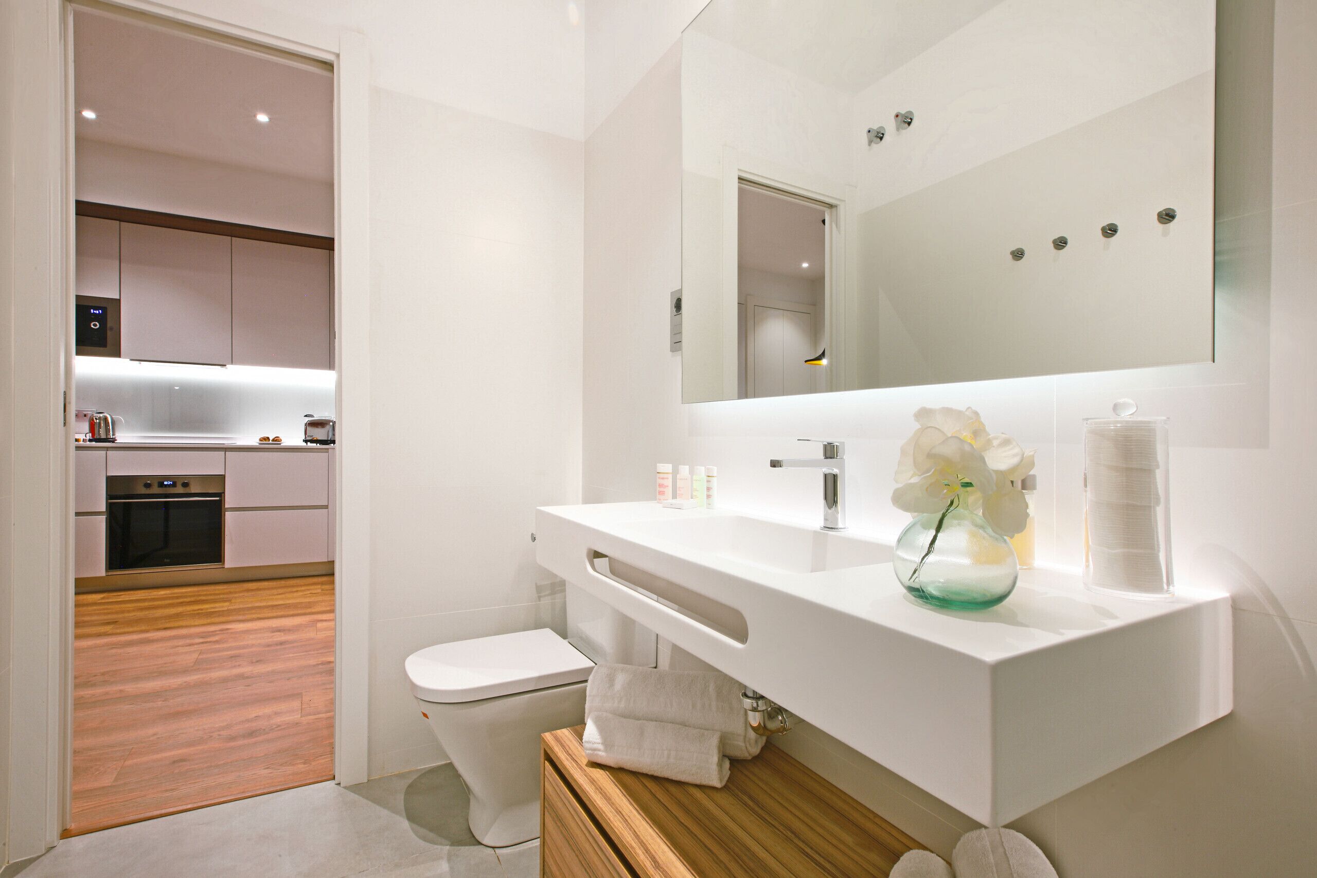 A modern bathroom with a white sink, mirror, and toilet.