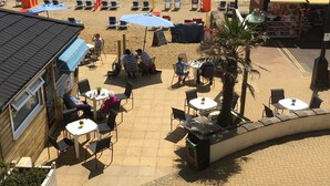 Un café frente a la playa con terraza, una pequeña tienda y vistas al mar.