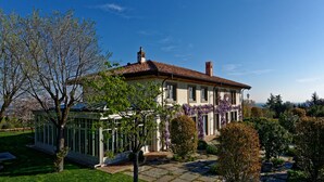 A two-story house with a tiled roof, a conservatory, and a well-maintained garden with various plants and a stone pathway.