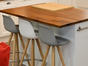 Une cuisine dotée d’un plan de travail en bois et de trois chaises grises aux pieds en bois.
