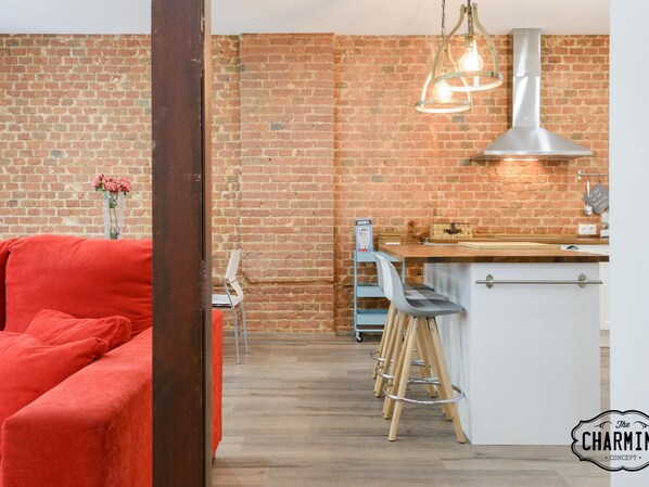 Une cuisine moderne avec un mur en briques, un canapé rouge et un coin bar avec des tabourets.