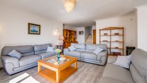 Un salon avec deux canapés gris, une table basse en bois, une lampe et une bibliothèque.