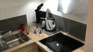A compact kitchen with a sink, stove, and a coffee maker. - Apartment Fernblick near Rosalie  (Ottobeuren)