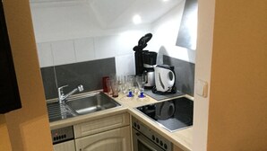 A compact kitchen with a dishwasher, oven, and a coffee maker. - Apartment Fernblick near Rosalie  (Ottobeuren)