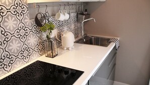 A kitchen with a black stove, white countertop, and patterned backsplash. - Stylish design apartment (Trier)