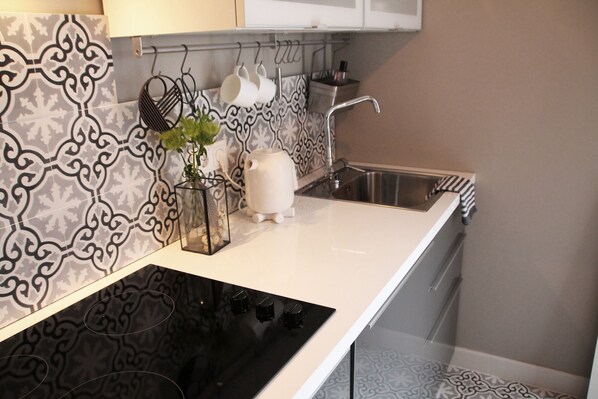 A kitchen with a black stove, white countertop, and patterned backsplash. - Stylish design apartment (Trier)
