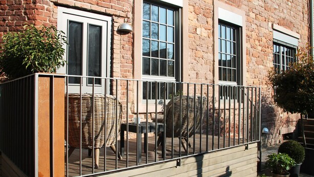 A balcony with wicker furniture and a railing. - Stylish design apartment (Trier)