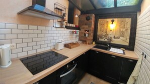 Ett kompakt kök med en svart spis, en bänkskiva i trä, en svart ugn och ett fönster med utsikt över stadsbilden.