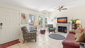 A living room with a fireplace, two armchairs, a sofa, a television, and a ceiling fan. - Best Value in Clearwater/ St. Pete Region! (Madeira Beach)