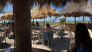 A beachside restaurant with thatched umbrellas and wooden tables. - Best Value in Clearwater/ St. Pete Region! (Madeira Beach)