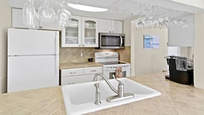 A modern kitchen with white cabinets, a stainless steel refrigerator, a microwave, an oven, and a sink with a faucet. - Best Value in Clearwater/ St. Pete Region! (Madeira Beach)