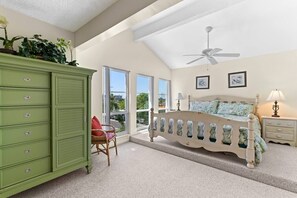 A bedroom with a bed, a green dresser, a chair, and a ceiling fan.