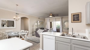 A modern kitchen with a dishwasher, a dining area with a white table and chairs, and a ceiling fan. - Workout room, yr round pool and spa, 2 Bd, 2 Bath, Gated, 9 AM-PM chk in-out (Phoenix)