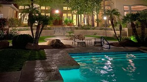 A nighttime view of a resort with a swimming pool, palm trees, and a building with illuminated windows. - Workout room, yr round pool and spa, 2 Bd, 2 Bath, Gated, 9 AM-PM chk in-out (Phoenix)