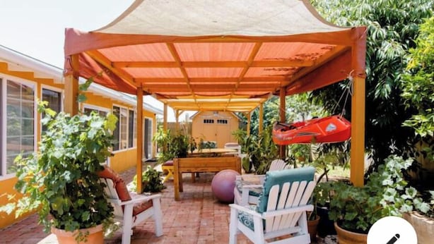 A covered patio area with a table and chairs, surrounded by potted plants and a yellow building in the background. - 20 minutes from downtown San Diego.Large clean quiet secured studio.Near 54H 125 (Spring Valley)