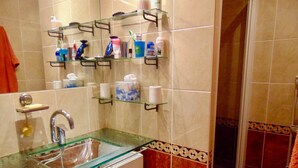 A bathroom with a glass sink, shelves with toiletries, and a shower area. - “L’Authentique”: soothing and rural! Air conditioning and free/secure parking! (Villeurbanne)