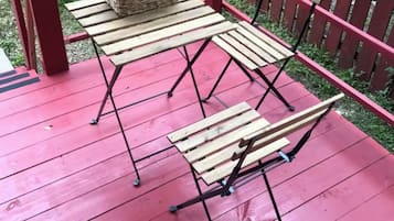 Un tavolo e sedie di legno all'aperto con un cesto su un patio rosso.