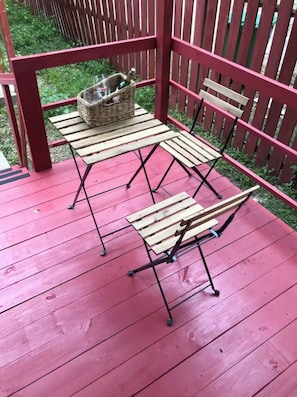 Mesa y sillas de madera al aire libre con una cesta en una terraza roja.