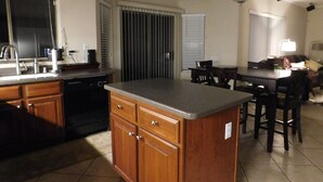 A kitchen with wooden cabinets, a built-in dishwasher, and a dining area with a table and chairs. - Classy and Comfortable, Gated 4-Bdrm Home, Heated Pool Family-Friendly (Mesa)