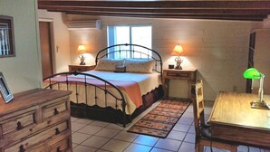 A bedroom with a bed, bedside tables, a desk, a chair, and a window.