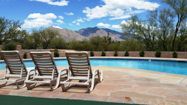 A pool area with lounge chairs and a view of mountains.