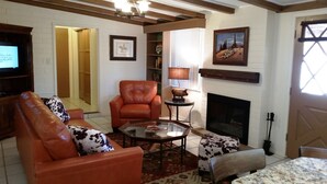 A living room with a fireplace, leather armchair, and a coffee table.