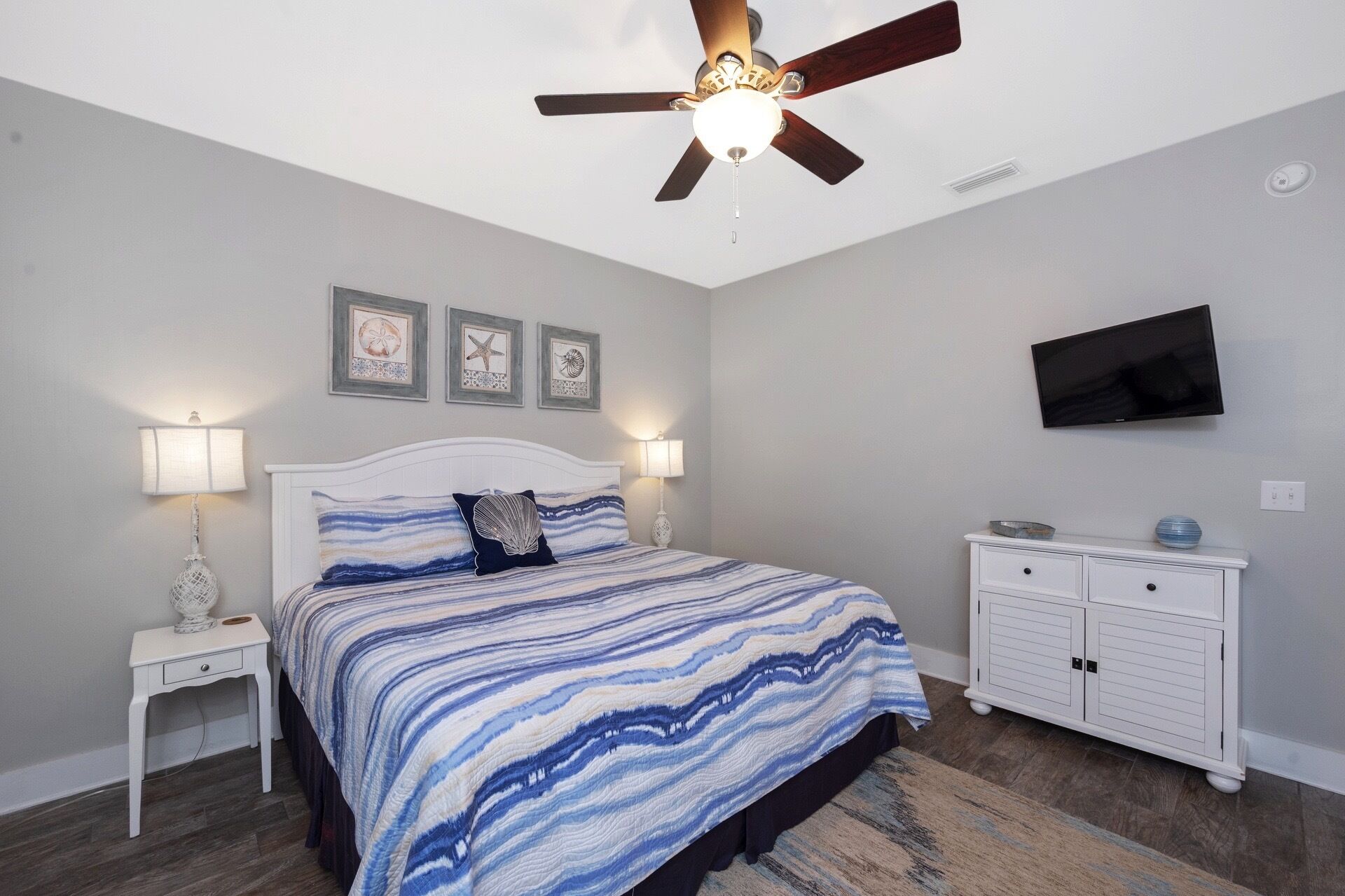A bedroom with a bed, a ceiling fan, a TV, a nightstand, and a dresser.