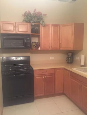 A kitchen with wooden cabinets, a black stove, a microwave, and a coffee maker.