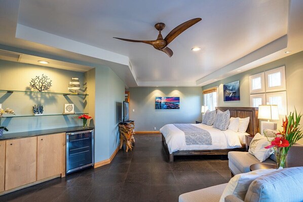 A modern bedroom with a large bed, a desk, and a ceiling fan.