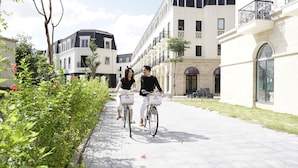 A paved pathway with bicycles, a building with balconies, and a garden area. - Soleil House Hostel (Hue)