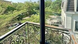 A balcony with wrought iron railings overlooking a lush green landscape and a distant mountain. - Soleil House Hostel (Hue)