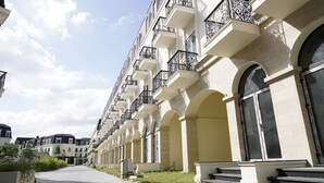 A row of multi-story buildings with balconies, arched windows, and a paved pathway. - Soleil House Hostel (Hue)