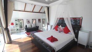 Un dormitorio con cama, mesita de noche, armario, sofá y ventana con cortinas.