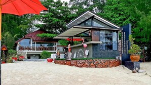 Un bar moderno con fachada de piedra, un paraguas rojo y un cartel que dice 'Phangan Bar'.