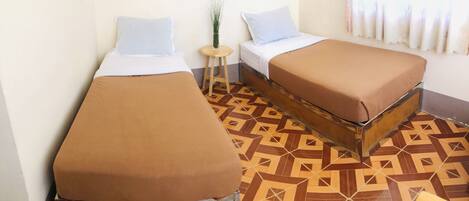 A room with two beds, a small stool, and a patterned floor.