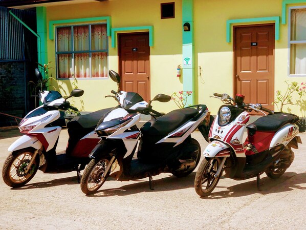 Three scooters parked in front of a building with two doors, one labeled 101 and the other 102.
