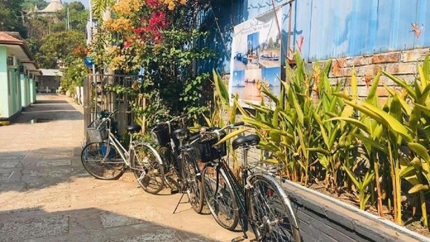 Bicycles parked along a sidewalk next to a building with a blue exterior. - Pinlon Pann motel (Mawlamyine)
