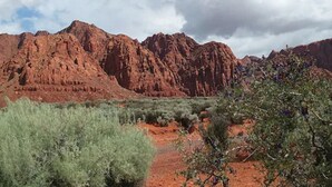 A desert landscape with red rock formations and sparse vegetation. - Zion's Cozy Cabins (Hildale)
