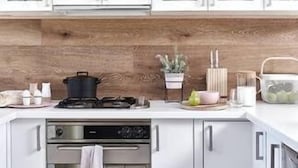 Eine moderne Küche mit weißen Schränken, einer Holzrückwand und Edelstahlgeräten.