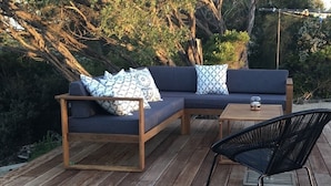 Eine Holzterrasse mit einem dunkelblauen Sofa und einem schwarzen Sessel.