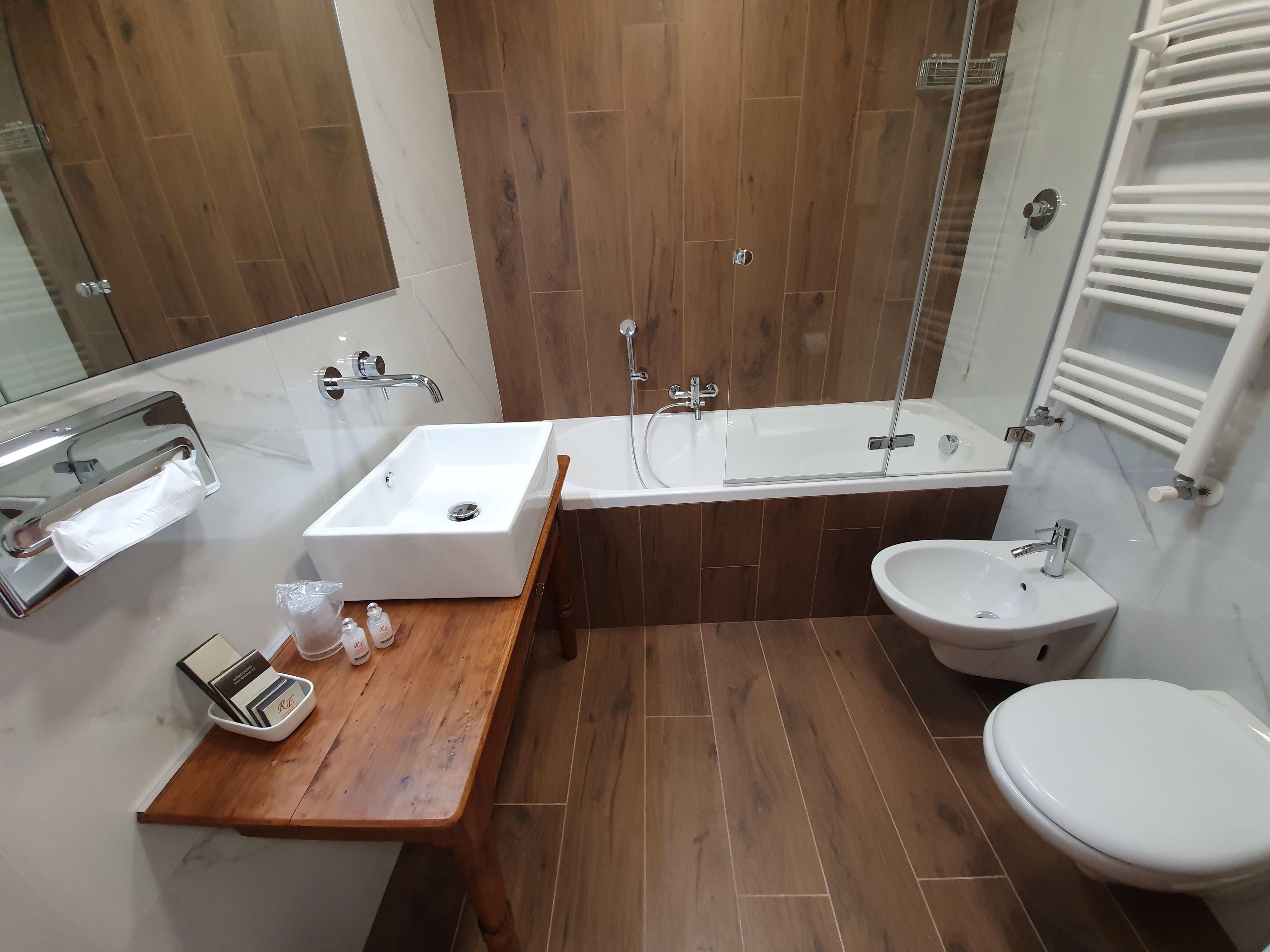 Een moderne badkamer met een houten wastafel, een wastafel, een badkuip, een douche en een toilet.