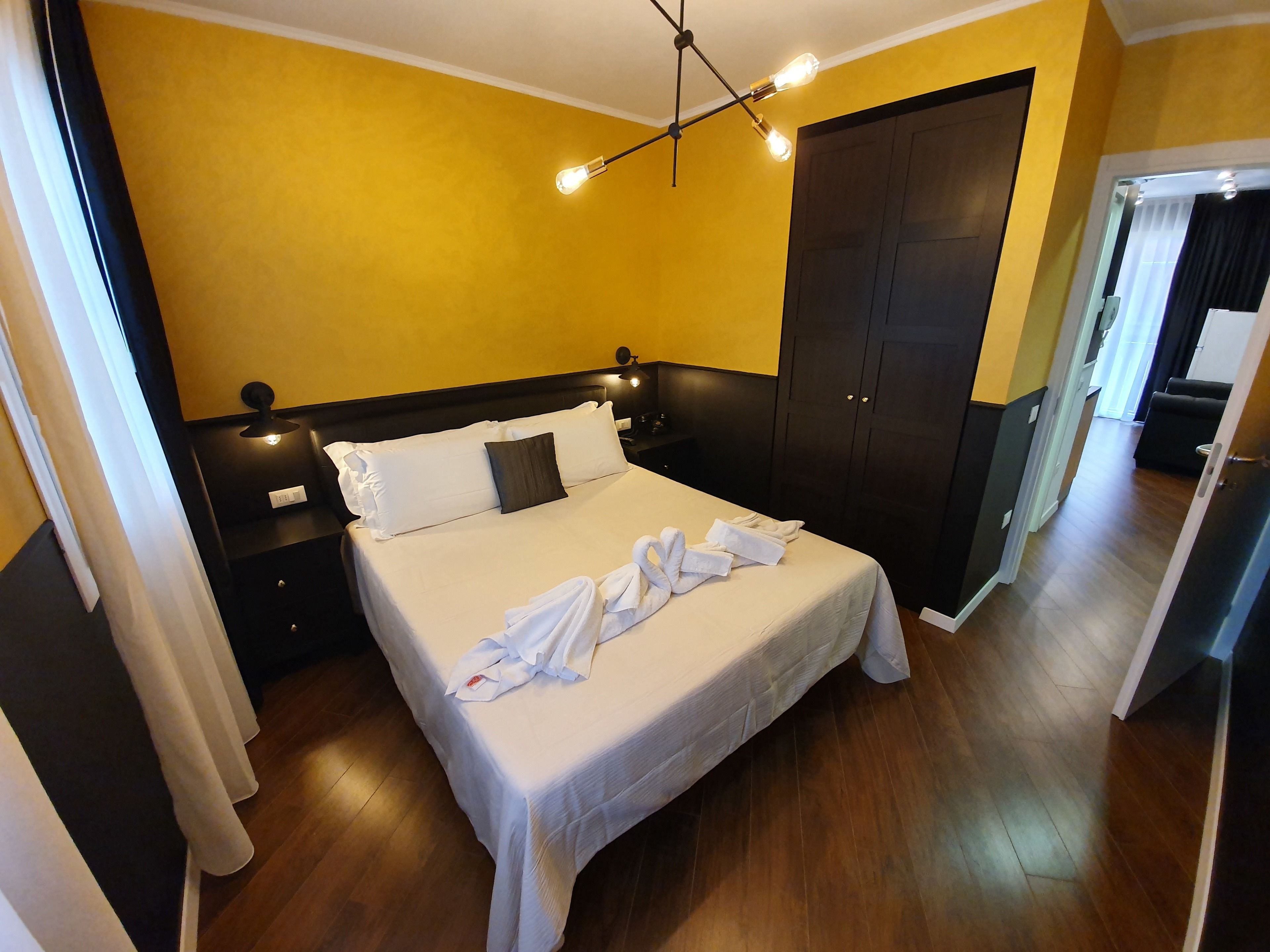 Une chambre d’hôtel comprenant un lit, une table de chevet, une armoire et une porte donnant sur une autre pièce.